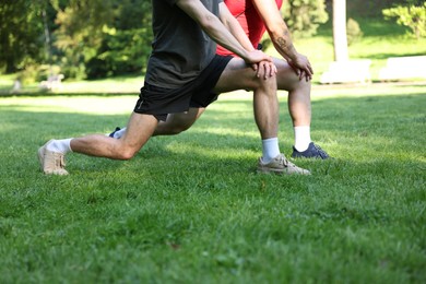 Photo of Young man exercising with professional personal trainer outdoors, closeup
