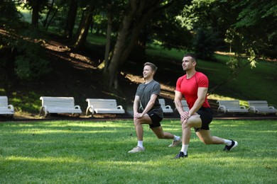 Photo of Young man exercising with professional personal trainer outdoors. Space for text