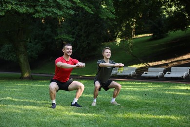 Photo of Young man exercising with professional personal trainer outdoors
