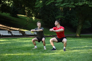 Photo of Young man exercising with professional personal trainer outdoors