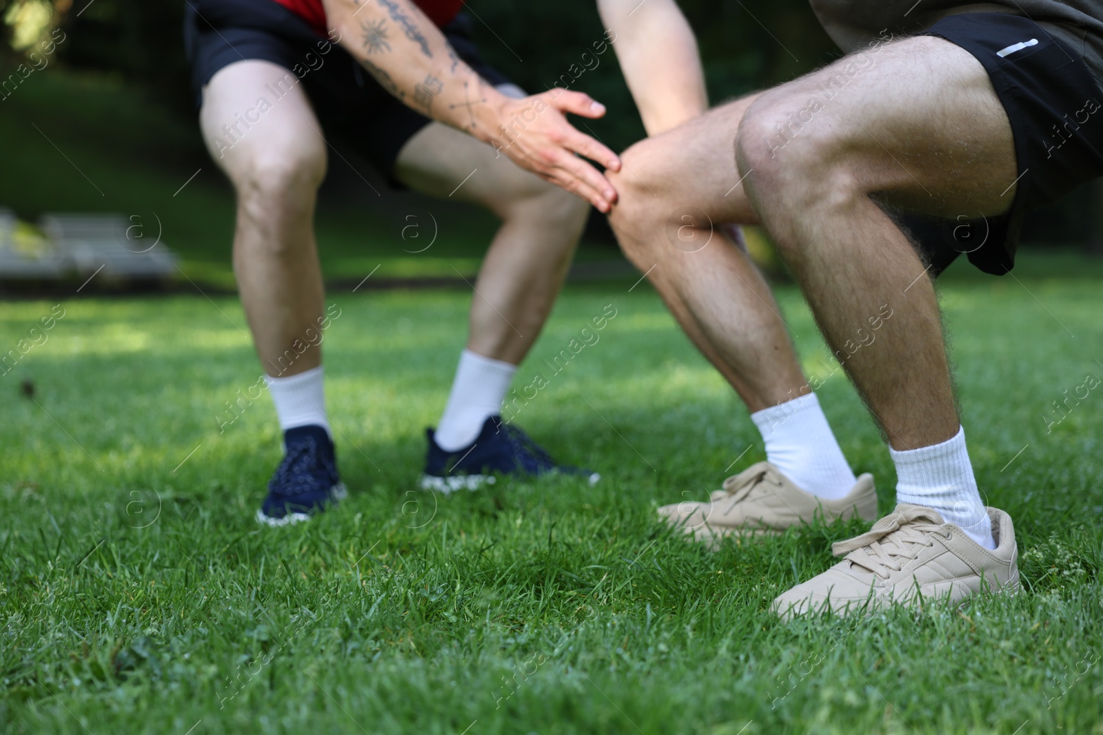 Photo of Young man exercising with professional personal trainer outdoors, closeup