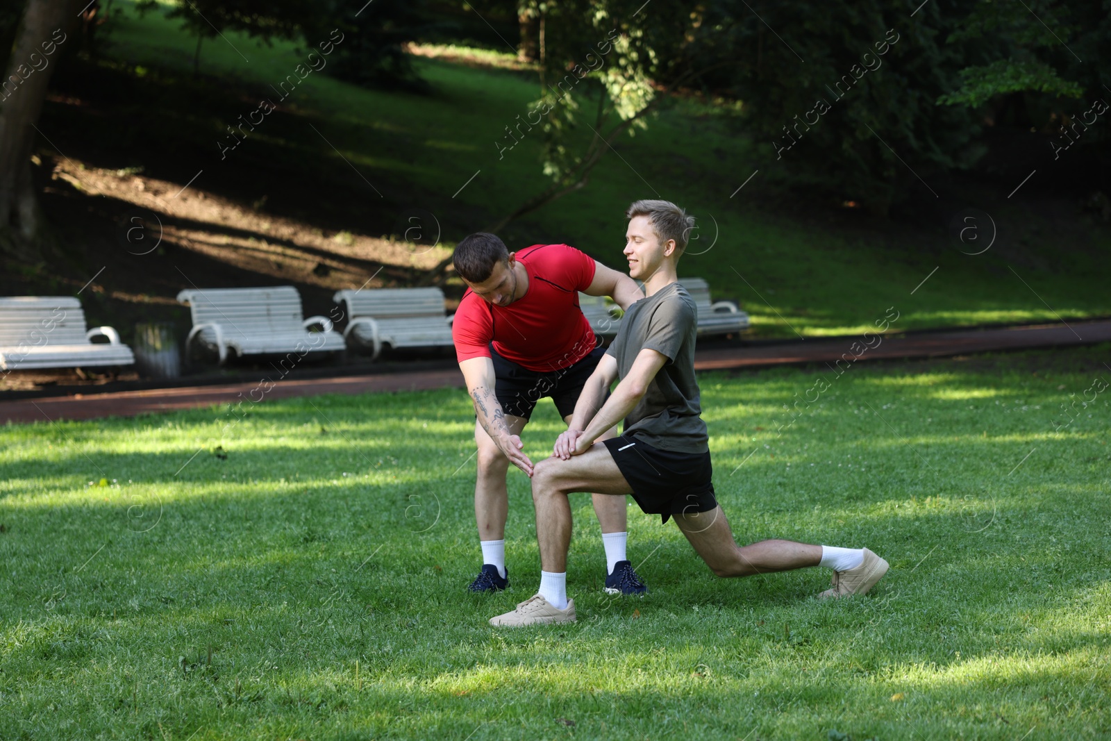 Young man exercising with professional personal trainer outdoors Photo of Young man exercising with professional personal trainer outdoors
