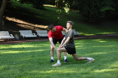 Photo of Young man exercising with professional personal trainer outdoors