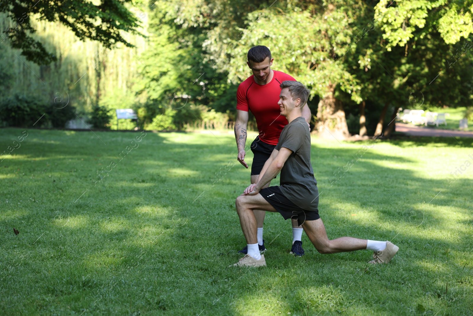 Young man exercising with professional personal trainer outdoors. Space for text Photo of Young man exercising with professional personal trainer outdoors. Space for text