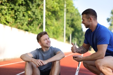 Photo of Young man exercising with professional personal trainer outdoors