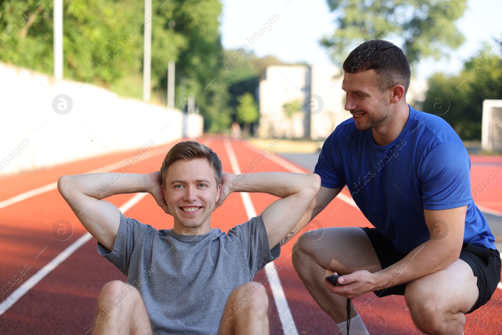 Young man exercising with professional personal trainer outdoors Photo of Young man exercising with professional personal trainer outdoors