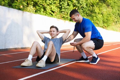 Photo of Young man exercising with professional personal trainer outdoors