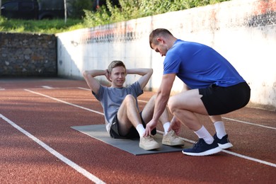 Photo of Young man exercising with professional personal trainer outdoors