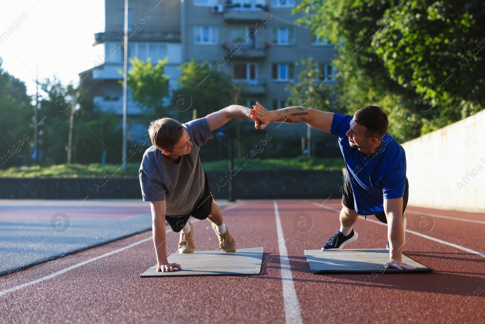 Young man with professional personal trainer giving high five outdoors Photo of Young man with professional personal trainer giving high five outdoors