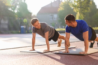 Photo of Young man exercising with professional personal trainer outdoors