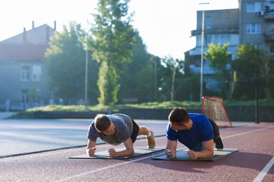 Photo of Young man exercising with professional personal trainer outdoors