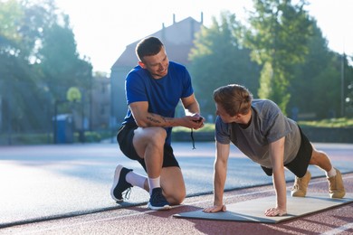 Photo of Young man exercising with professional personal trainer outdoors