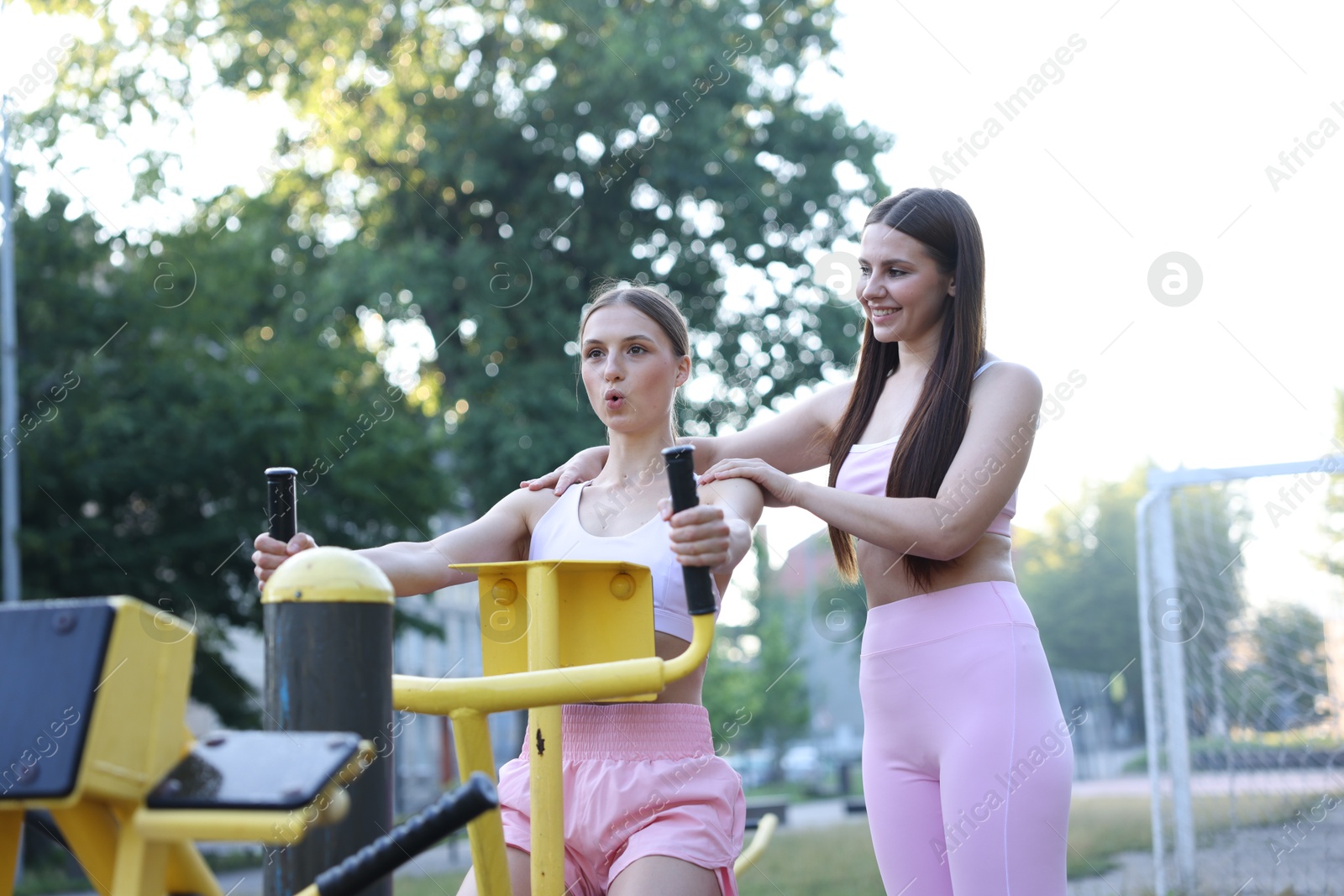 Young woman exercising with outdoor gym equipment with professional personal trainer outdoors Photo of Young woman exercising with outdoor gym equipment with professional personal trainer outdoors