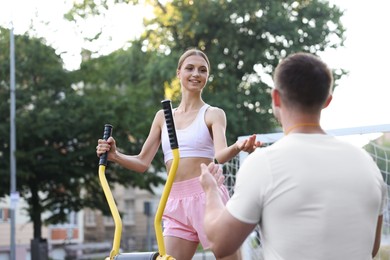 Photo of Young man exercising with outdoor gym equipment with professional personal trainer outdoors