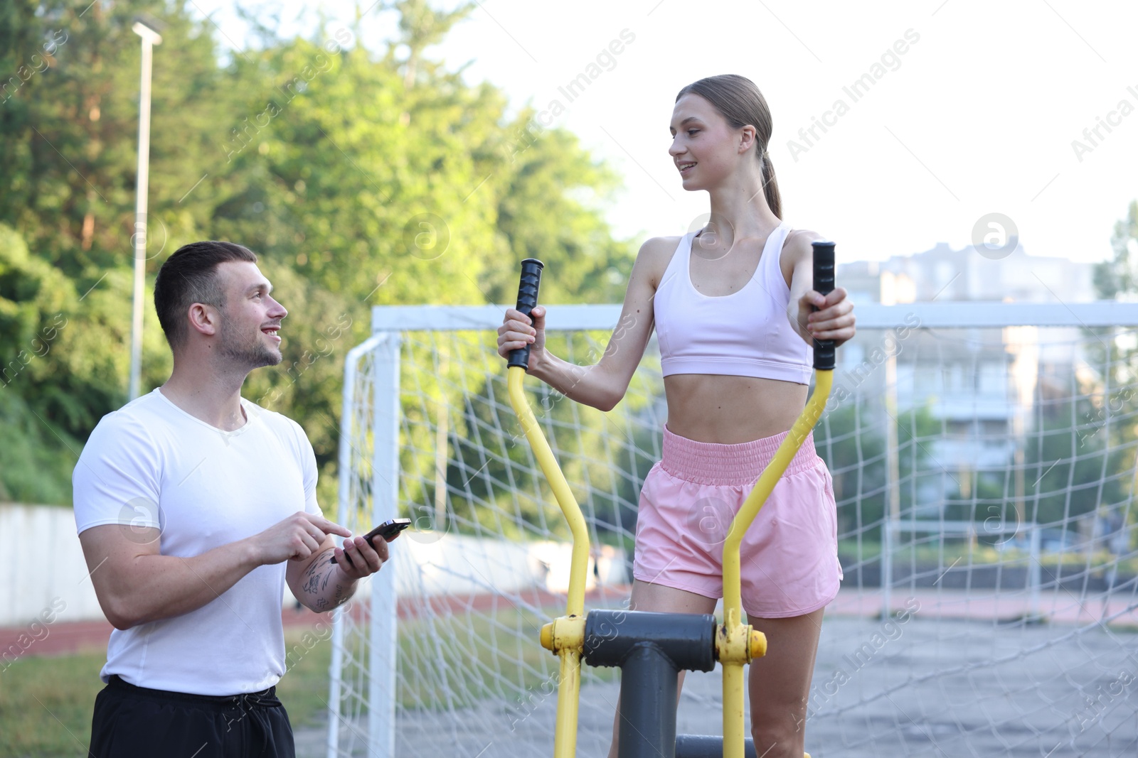 Young woman exercising with outdoor gym equipment with professional personal trainer outdoors Photo of Young woman exercising with outdoor gym equipment with professional personal trainer outdoors