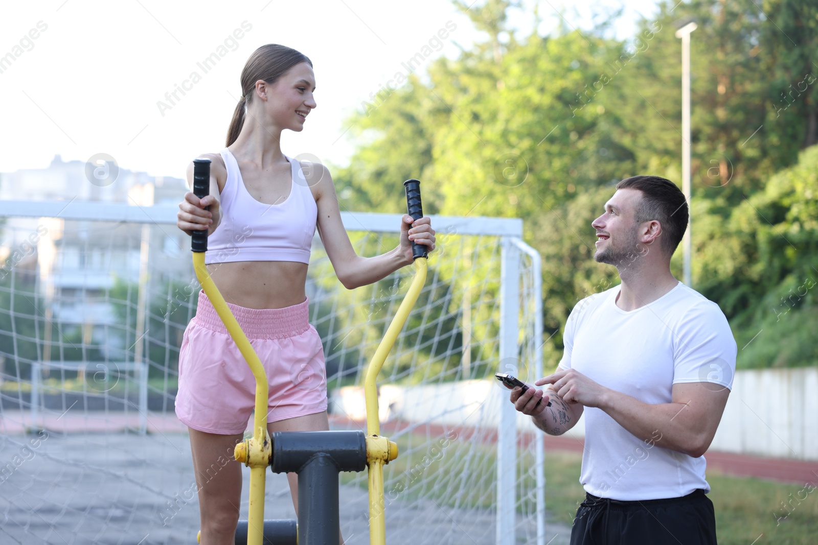 Young woman exercising with outdoor gym equipment with professional personal trainer outdoors Photo of Young woman exercising with outdoor gym equipment with professional personal trainer outdoors