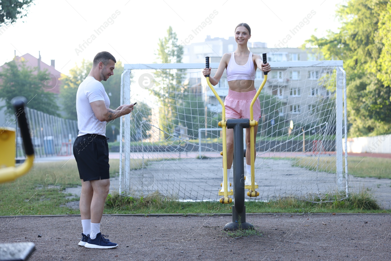 Young woman exercising with outdoor gym equipment with professional personal trainer outdoors Photo of Young woman exercising with outdoor gym equipment with professional personal trainer outdoors