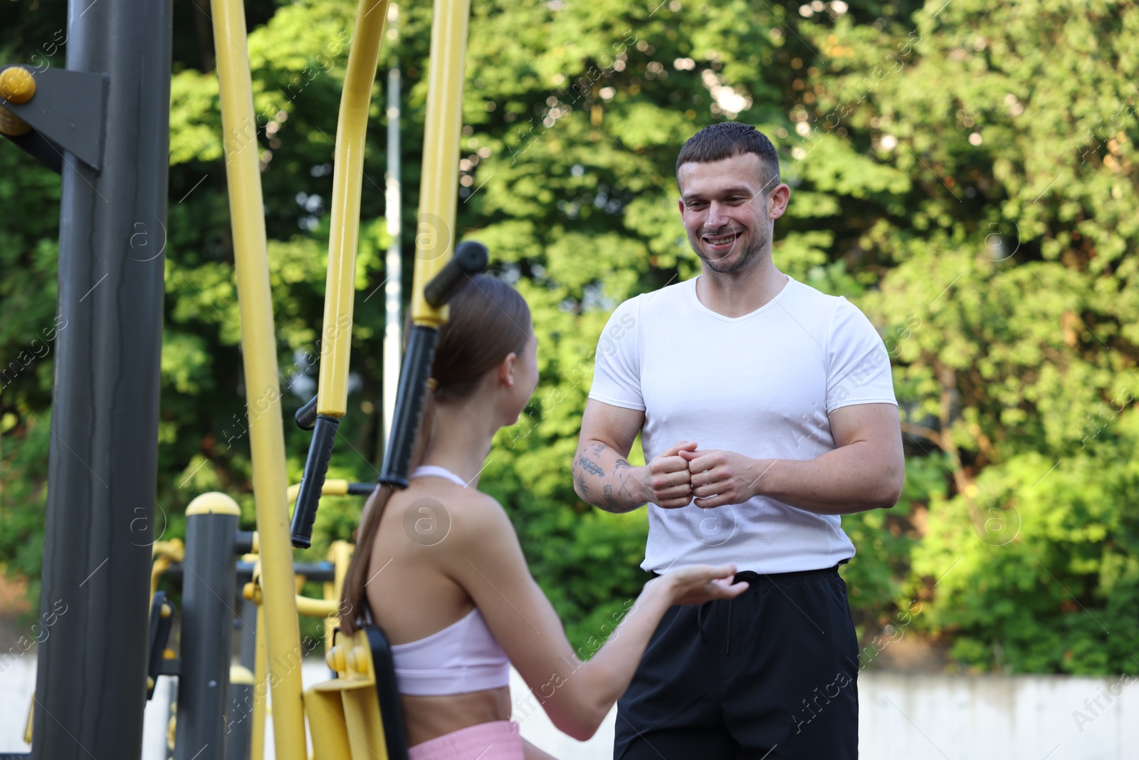Young woman exercising with outdoor gym equipment with professional personal trainer outdoors Photo of Young woman exercising with outdoor gym equipment with professional personal trainer outdoors