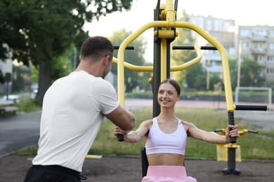 Photo of Young woman exercising with outdoor gym equipment with professional personal trainer outdoors