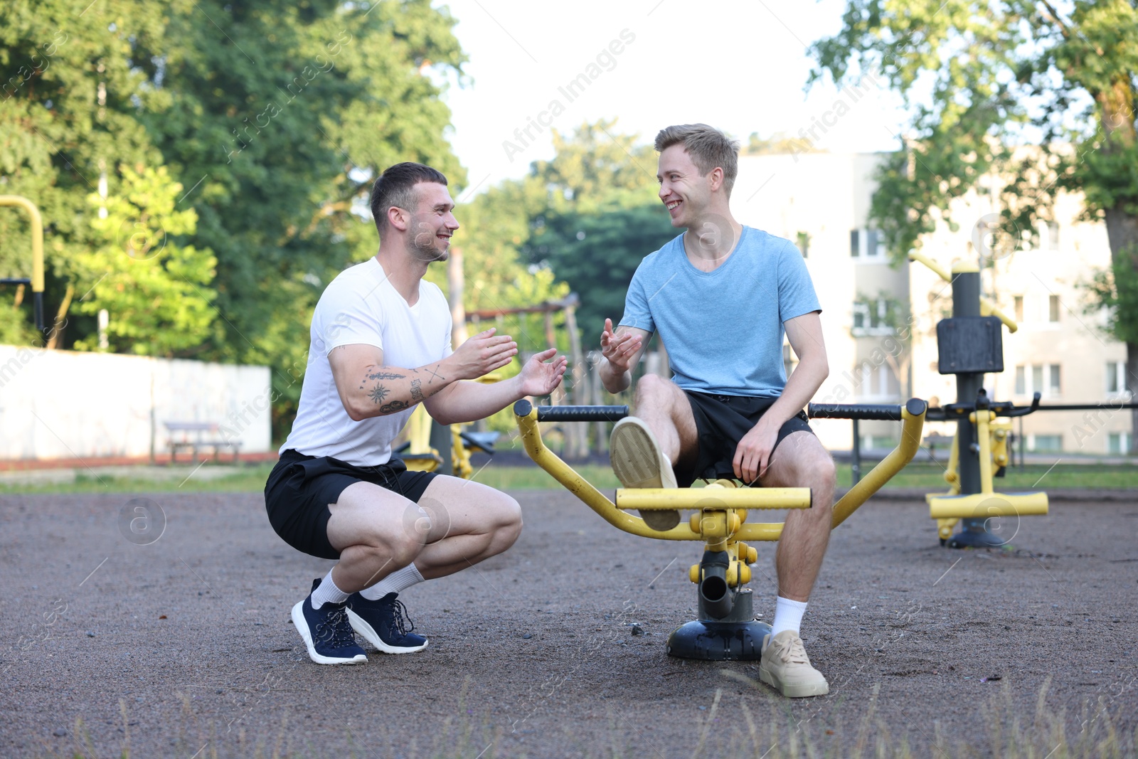 Young man exercising with outdoor gym equipment with professional personal trainer outdoors Photo of Young man exercising with outdoor gym equipment with professional personal trainer outdoors