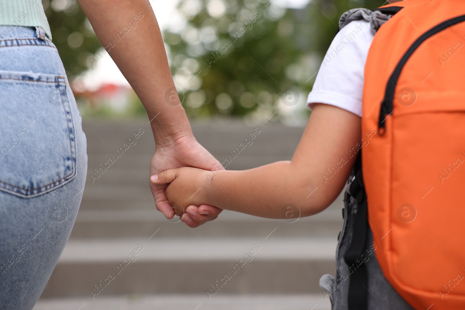 Mother holding hands with her daughter and taking her to school outdoors, closeup Photo of Mother holding hands with her daughter and taking her to school outdoors, closeup