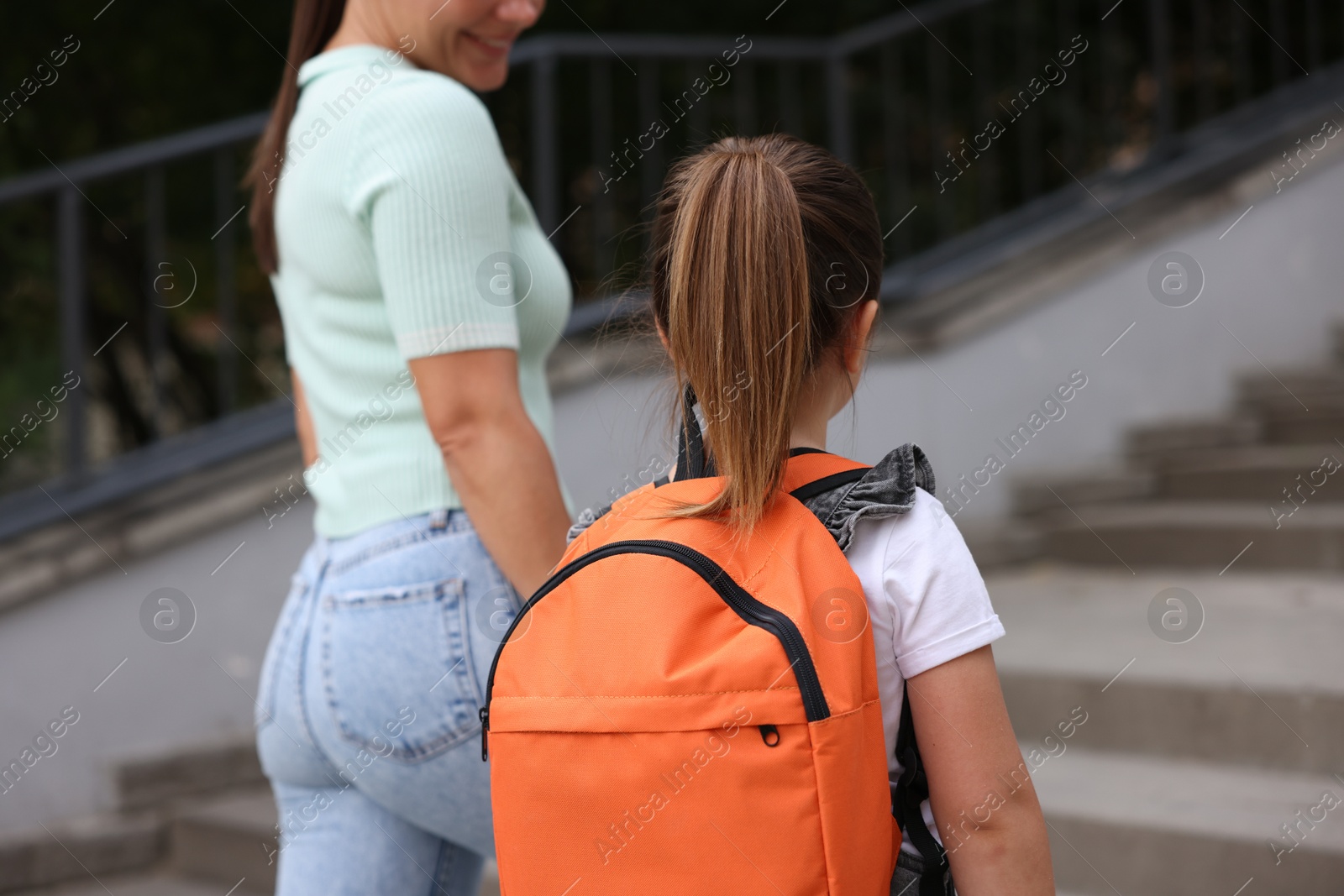Mother taking her daughter to school outdoors, back view Photo of Mother taking her daughter to school outdoors, back view