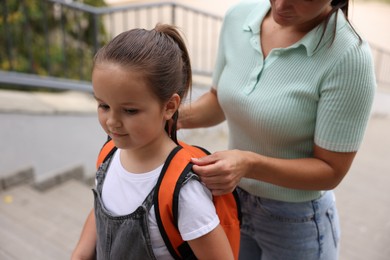 Photo of Mother taking her daughter to school outdoors, closeup