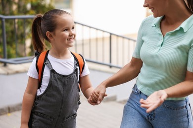 Photo of Mother taking her daughter to school outdoors, closeup
