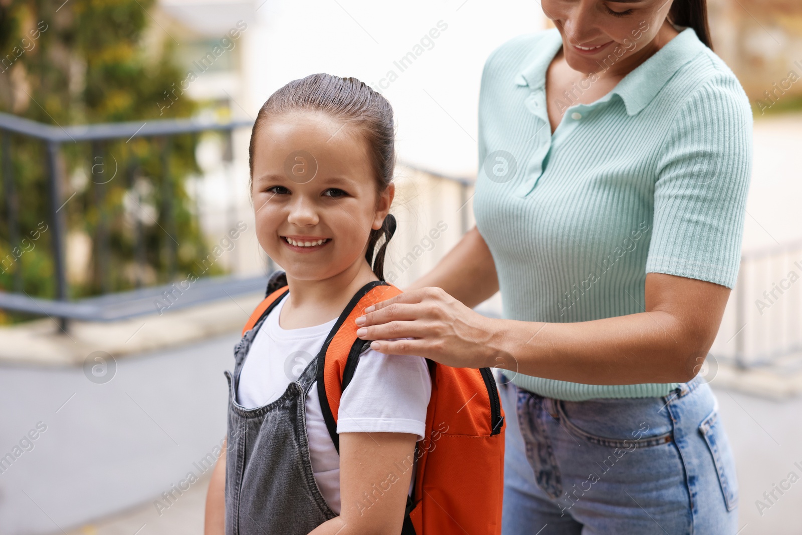 Mother taking her daughter to school outdoors, closeup Photo of Mother taking her daughter to school outdoors, closeup
