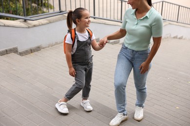 Photo of Mother taking her daughter to school outdoors, closeup