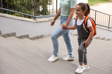 Photo of Mother taking her daughter to school outdoors, closeup