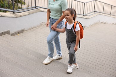 Photo of Mother taking her daughter to school outdoors, closeup