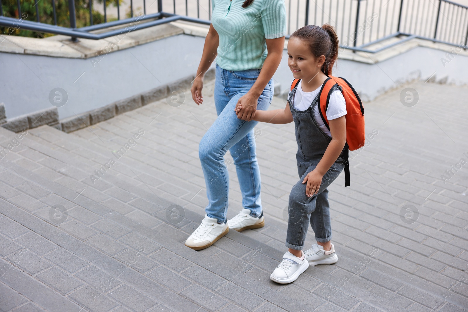 Mother taking her daughter to school outdoors, closeup Photo of Mother taking her daughter to school outdoors, closeup