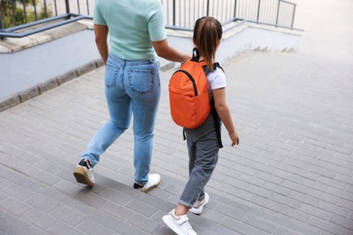Photo of Mother taking her daughter to school outdoors, back view