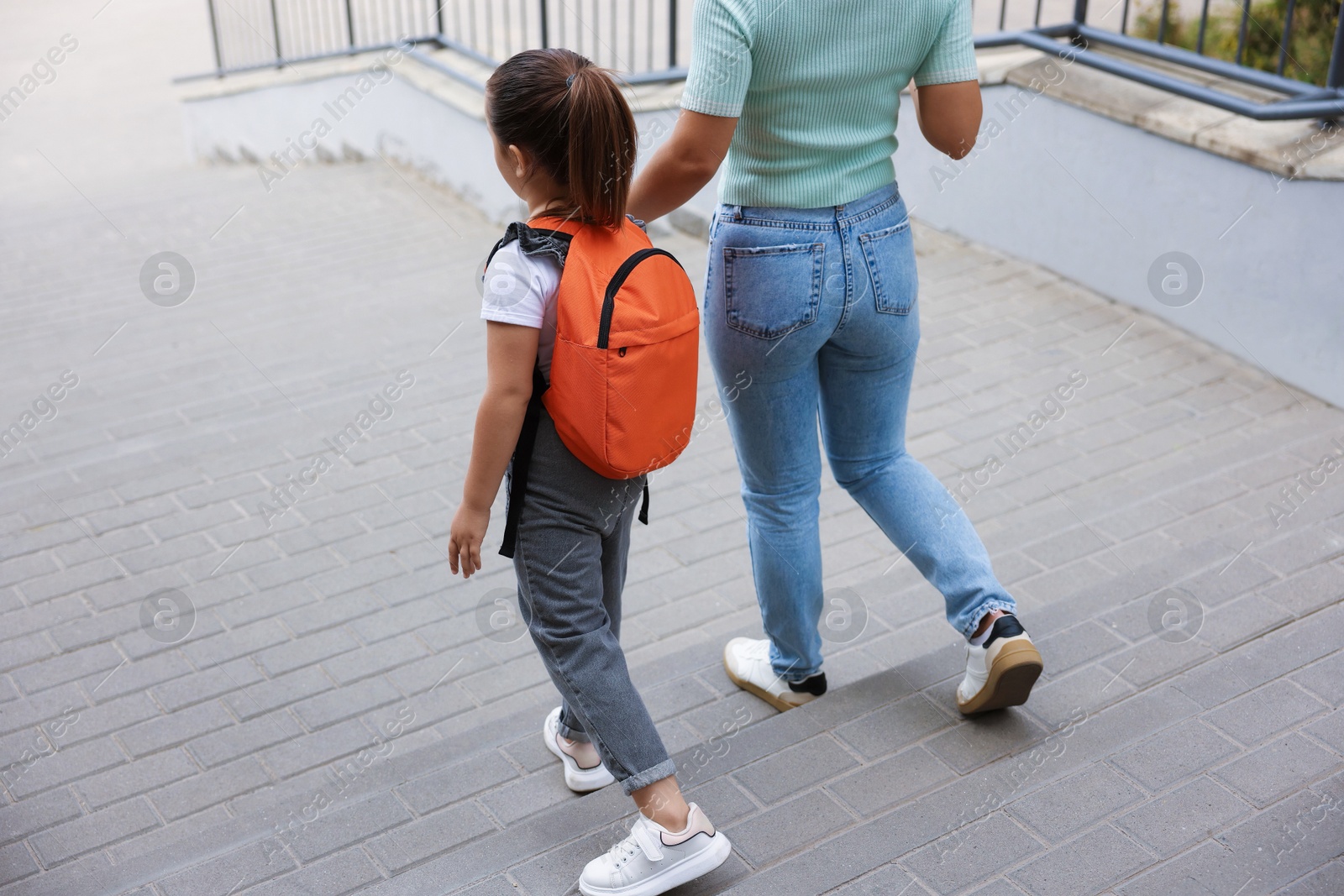 Mother taking her daughter to school outdoors, back view Photo of Mother taking her daughter to school outdoors, back view