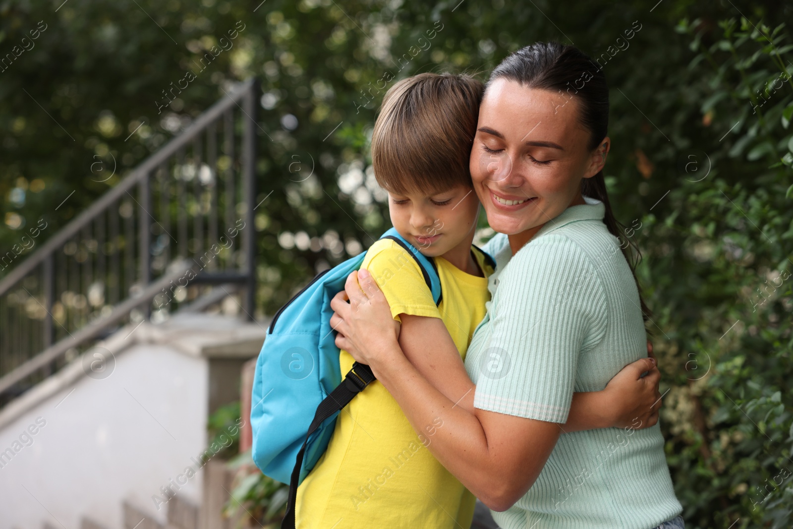 Photo of Mother hugging her son while taking him to school outdoors