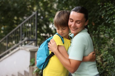 Photo of Mother hugging her son while taking him to school outdoors