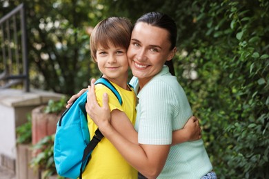 Photo of Mother hugging her son while taking him to school outdoors