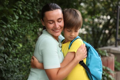 Photo of Mother hugging her son while taking him to school outdoors
