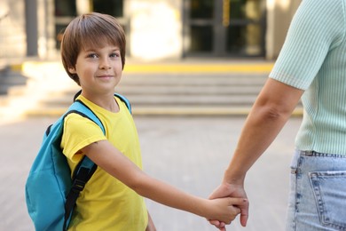 Photo of Mother taking her son to school outdoors, closeup