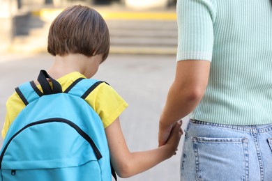 Photo of Mother taking her son to school outdoors, back view