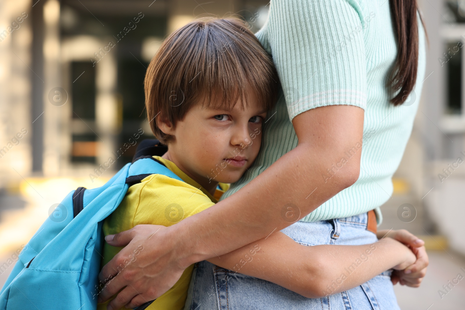 Mother hugging her son while taking him to school outdoors, closeup Photo of Mother hugging her son while taking him to school outdoors, closeup