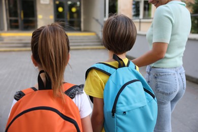 Photo of Mother taking her children to school outdoors, back view