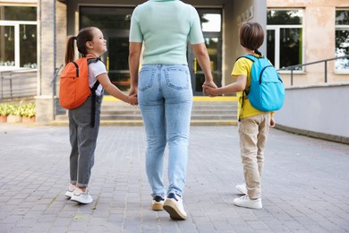 Photo of Mother taking her children to school outdoors, back view