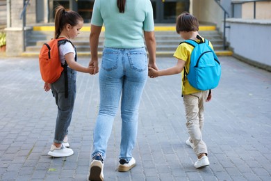 Photo of Mother taking her children to school outdoors, back view