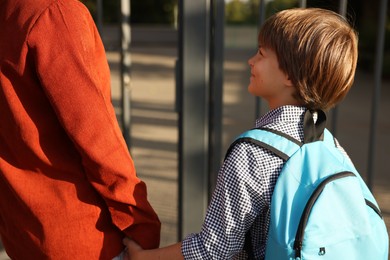 Photo of Mother taking her son to school outdoors, closeup