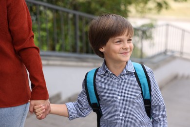 Photo of Mother taking her son to school outdoors, closeup