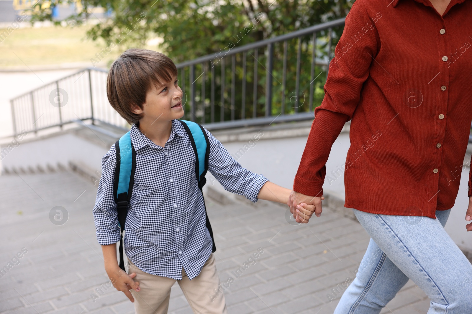 Photo of Mother taking her son to school outdoors, closeup