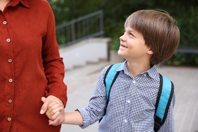 Photo of Mother taking her son to school outdoors, closeup