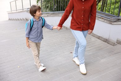 Photo of Mother taking her son to school outdoors, closeup